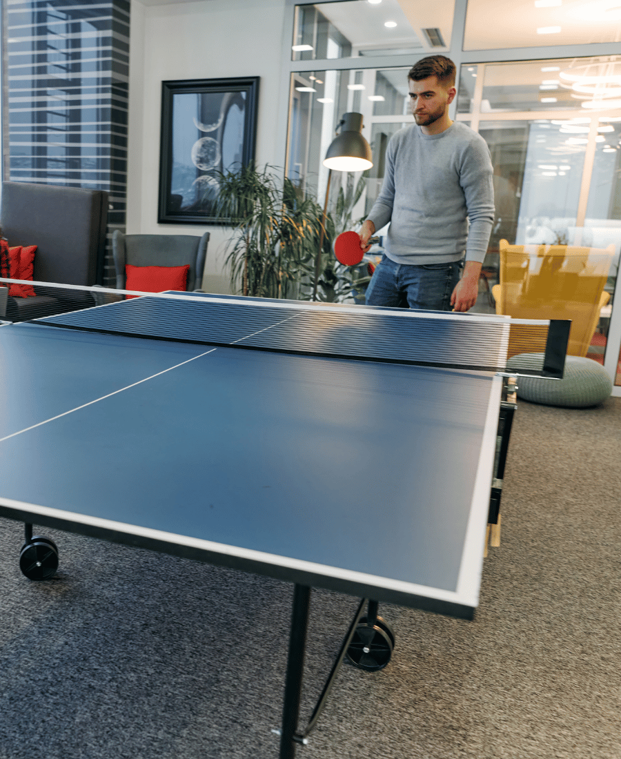 Business Colleagues Take a Break from Work to Enjoy a Game of Table Tennis, Fostering Teamwork and Camaraderie in the Workplace